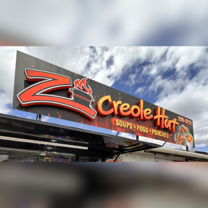 Large outdoor restaurant sign for Creole Hut featuring bold 3D lettering, a stylized “Z” logo with flame design, and text advertising soups, food, and punches against a vibrant background
